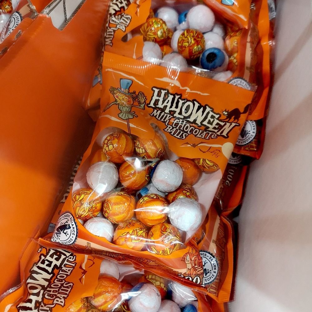 Bags of Halloween candy stacked on a store shelf