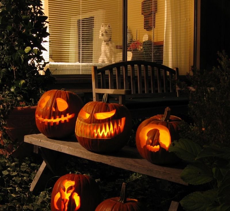 Carved jack-o-lanterns glowing on a front porch on Halloween night