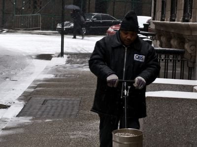 Worker spreading salt on a city sidewalk in winter (item type photo, not the exact product)